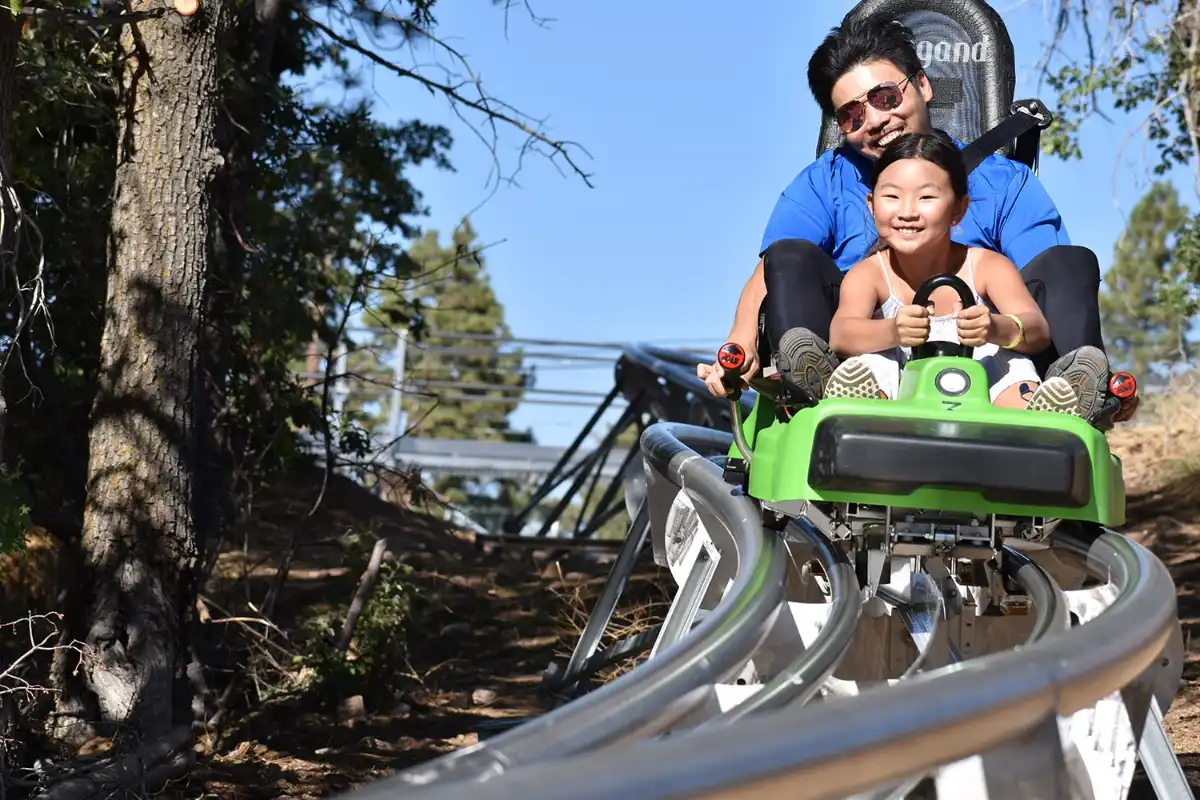 smiling man and child riding the canyon coaster