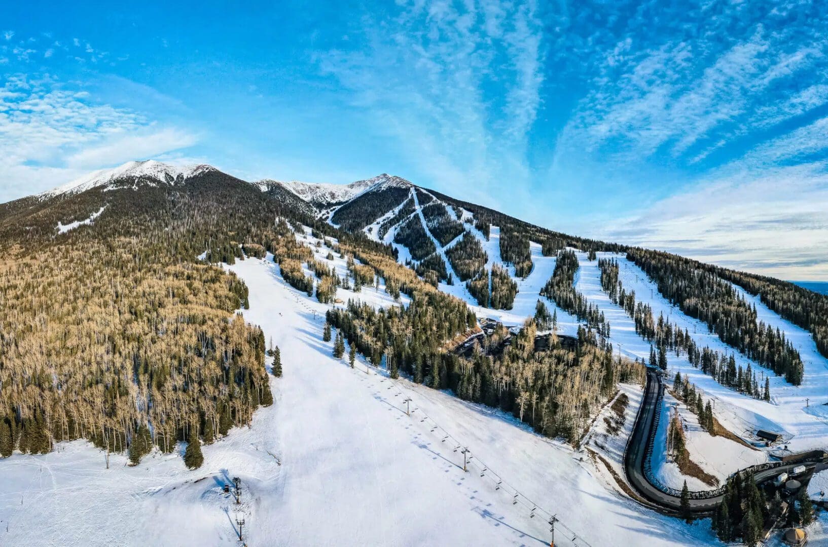snow covered mountain with ski trails, lifts, and trees