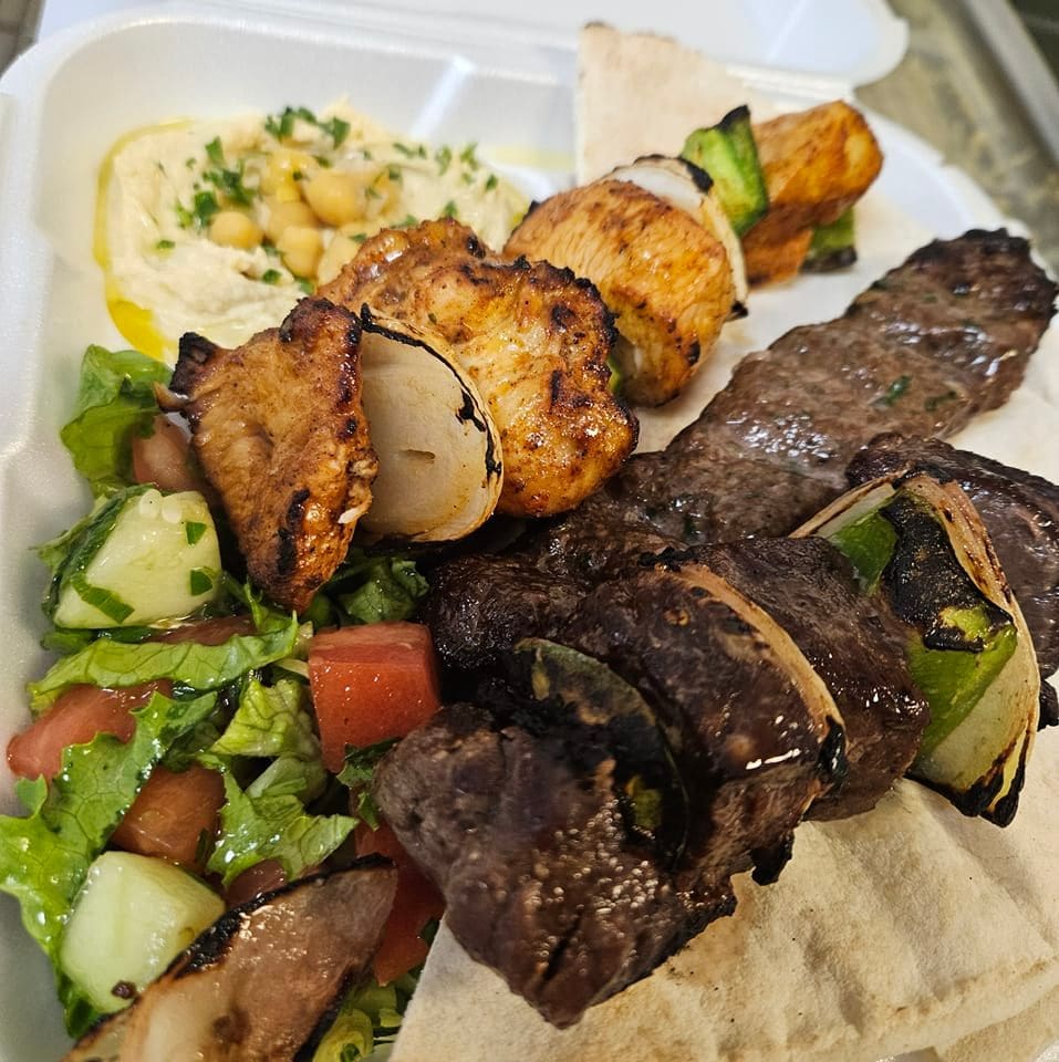 plate of kabobs with salad and hummus