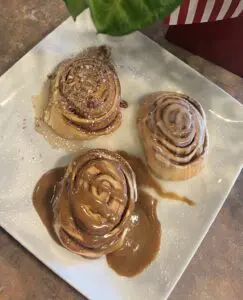 3 cinnamon rolls with frosting on a white plate